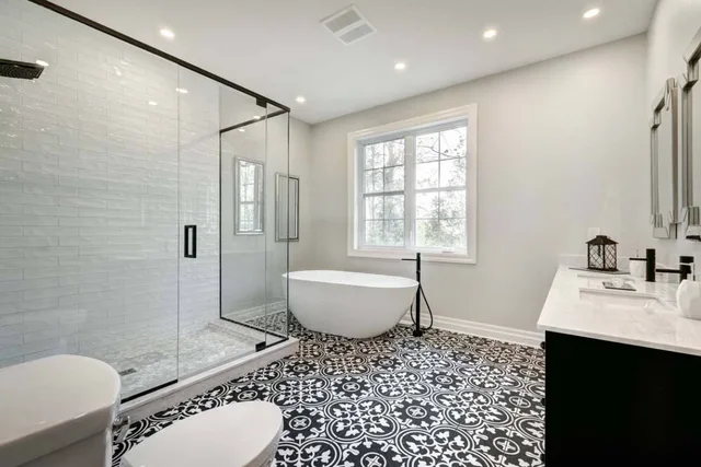 Bright bathroom with a glass shower, patterned floor and freestanding bathtub