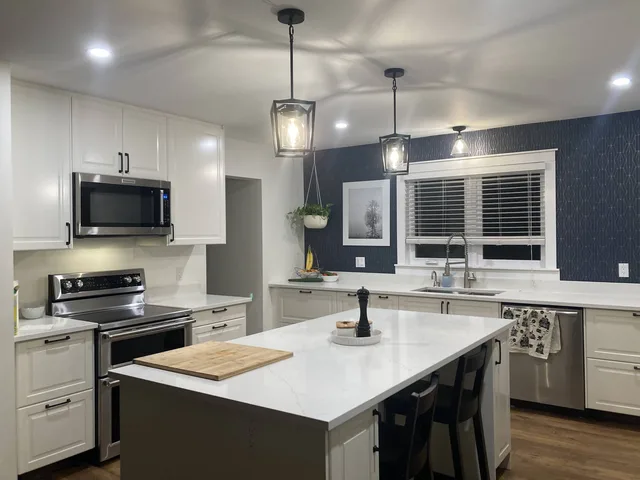 White kitchen with an island, pendant lights and contrasting dark walls